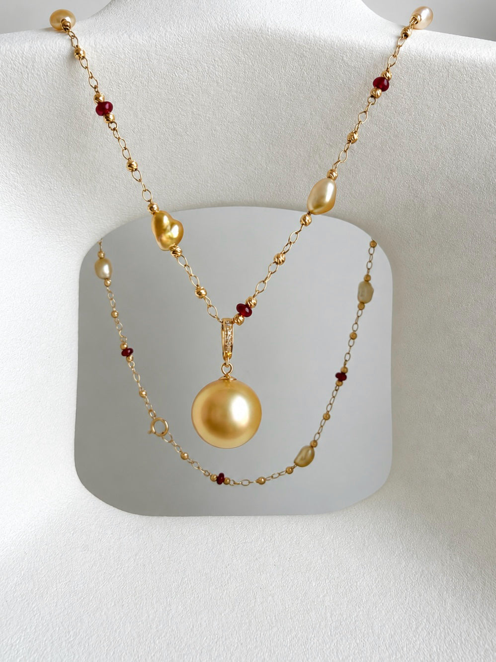 Multi-strand gold bead necklace with gold pearl center pendant and tiny red accents