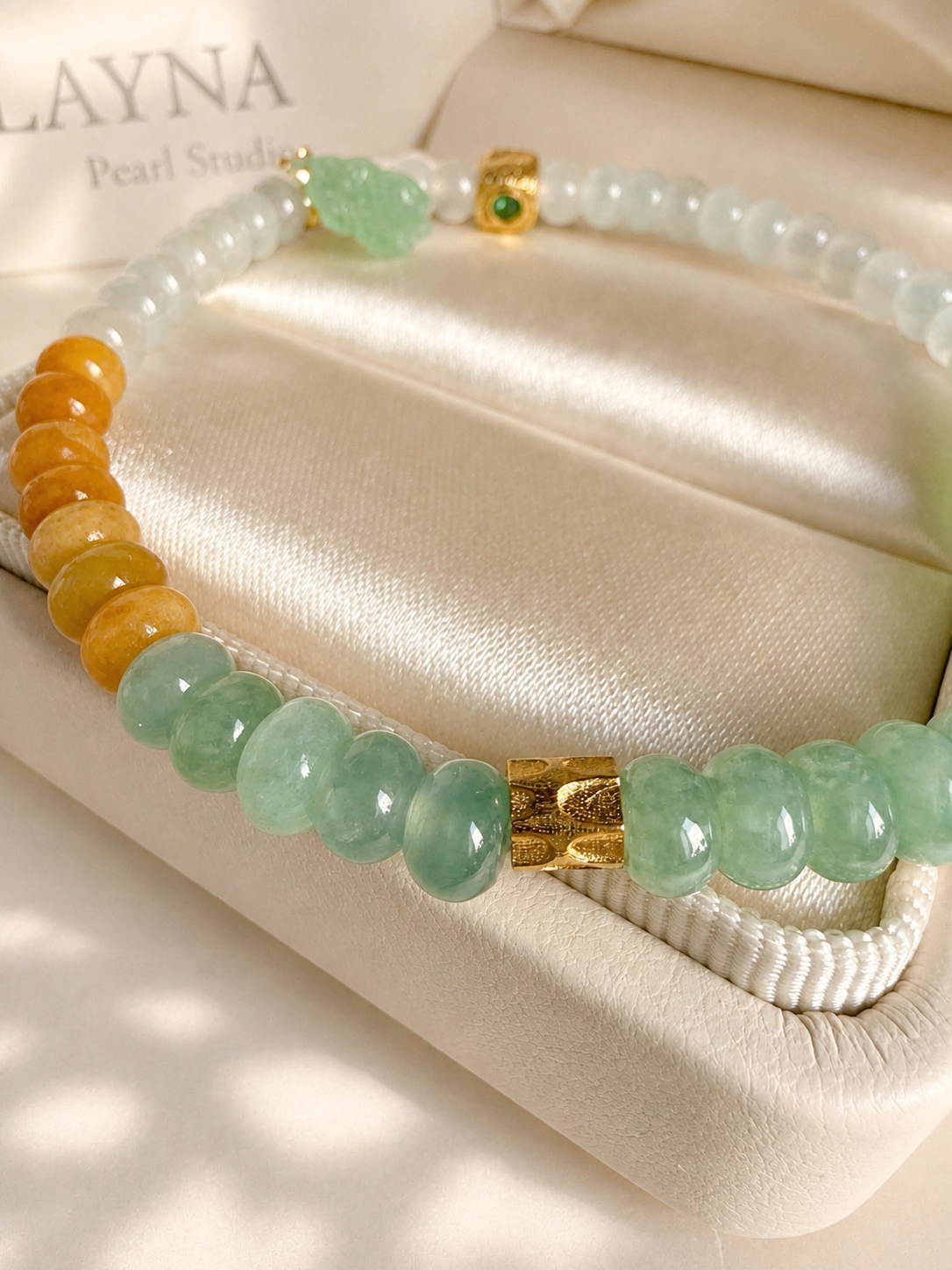 Jadeite beaded bracelet with mint green and orange beads, gold square charm, and tassels