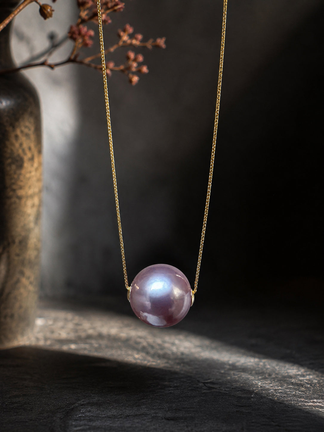 Gold necklace with purple pearl drop pendant centered on chain