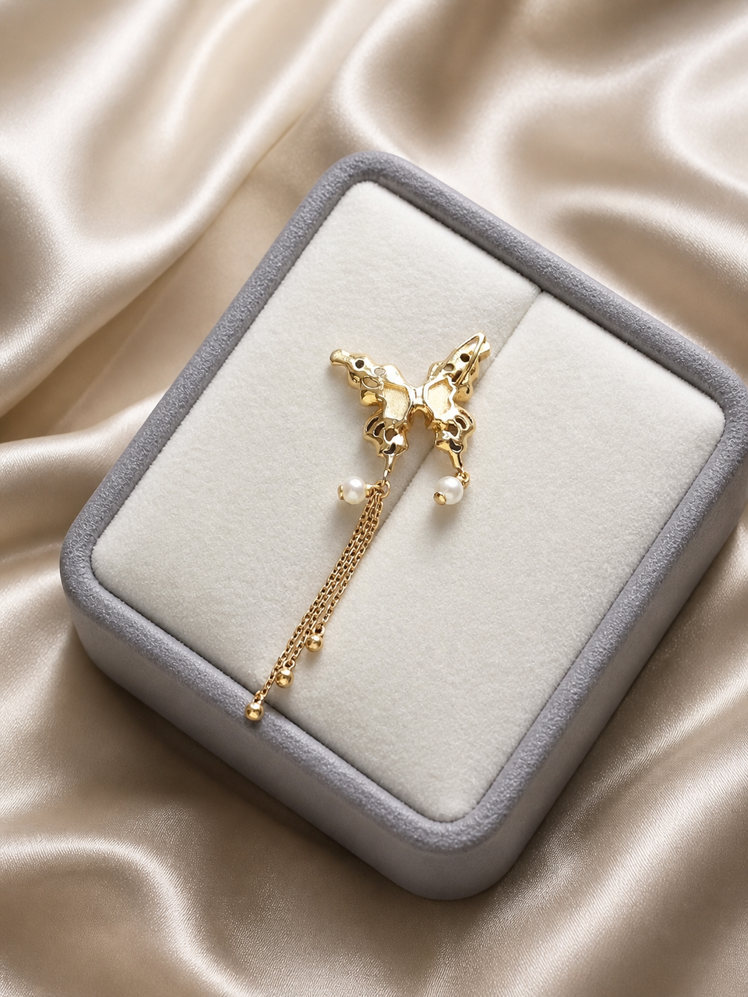 Gold butterfly pendant with pearl dangles and long chain tassel in jewelry box