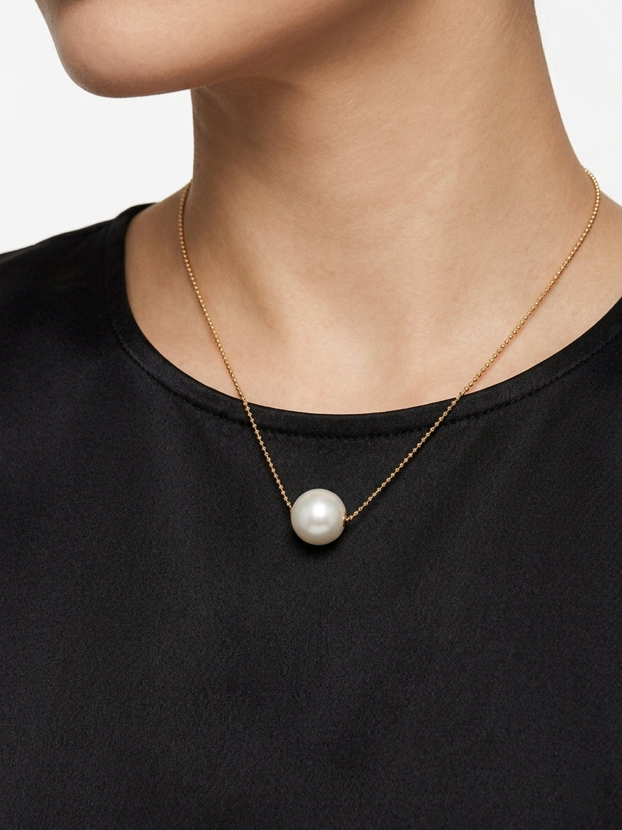 Gold-tone freshwater pearl pendant necklace worn with a black top