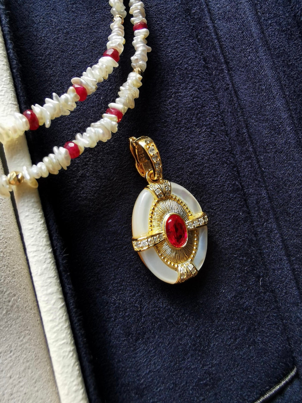 Close-up of keshi pearl necklace with red ruby beads and gold pendant detail
