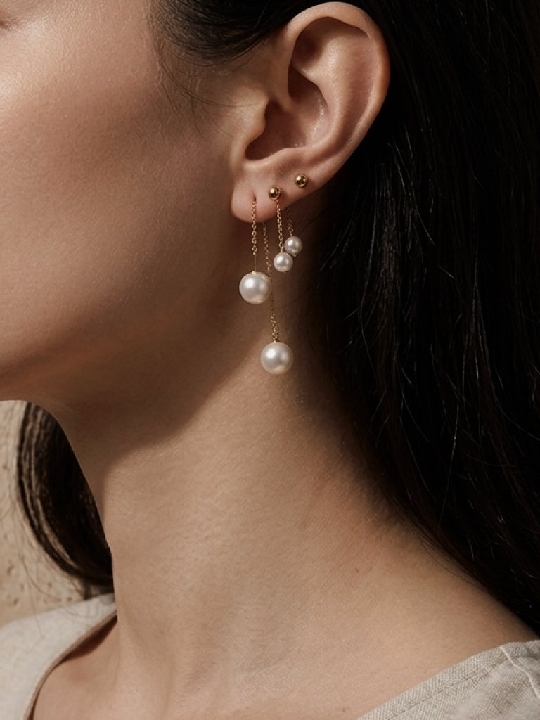 Long threader pearl earrings with gold-tone chain and a dangling pearl on ear
