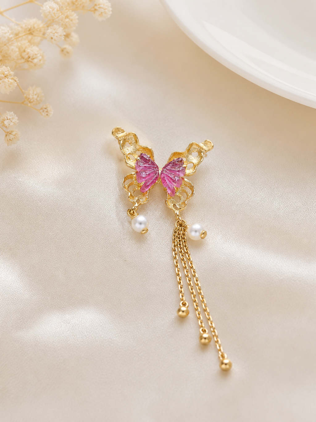 Gold butterfly pendant with pink center stones, pearl drops, and dangling chain tassels
