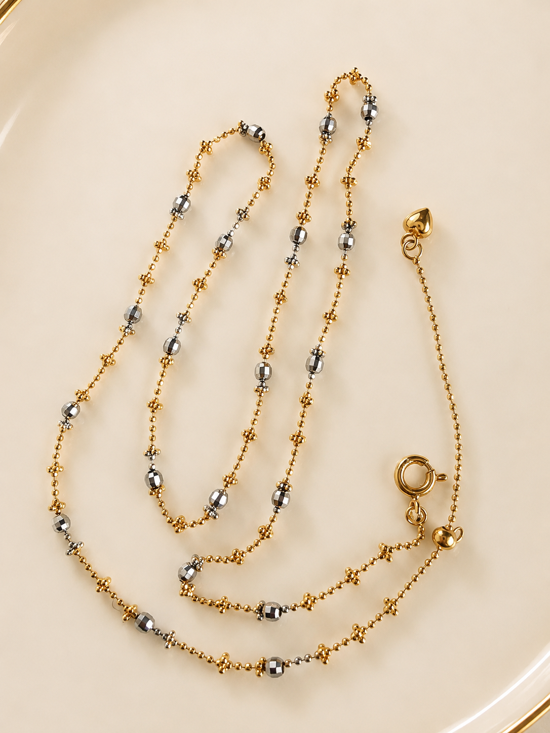 Layered beaded necklace with dark bead accents and gold-tone clasp and connector rings