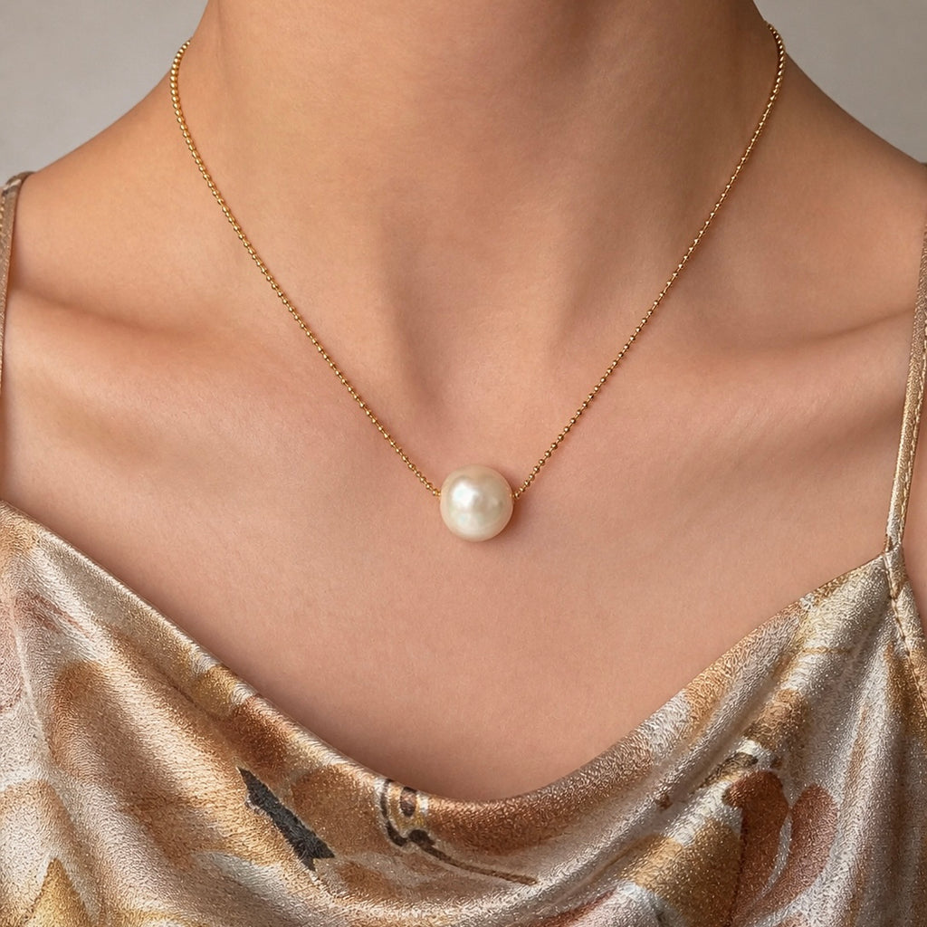 Gold-tone chain necklace with white freshwater pearl pendant at neckline