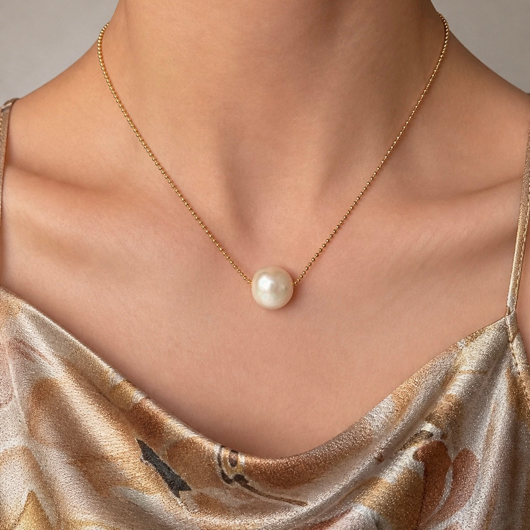 Gold-tone chain necklace with white freshwater pearl pendant at neckline
