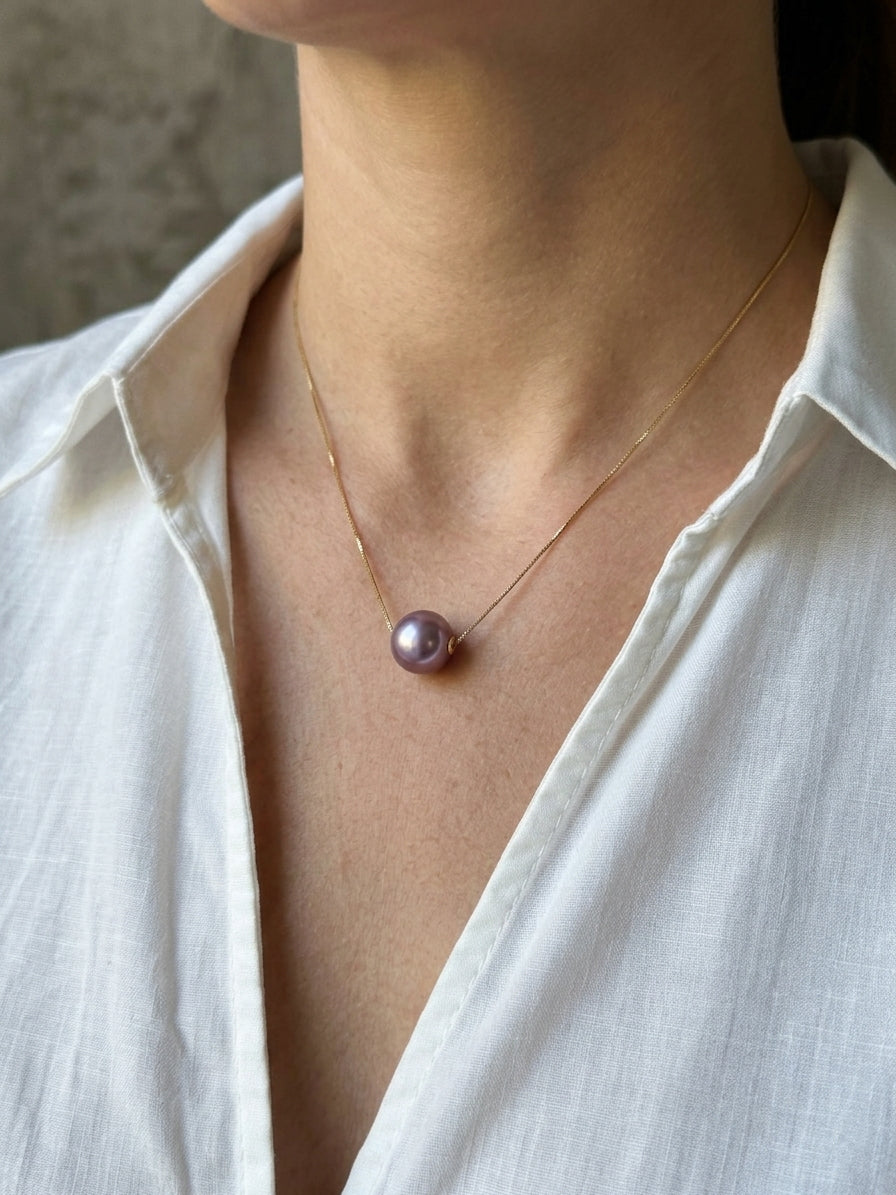 Gold chain necklace with purple round pearl pendant at center