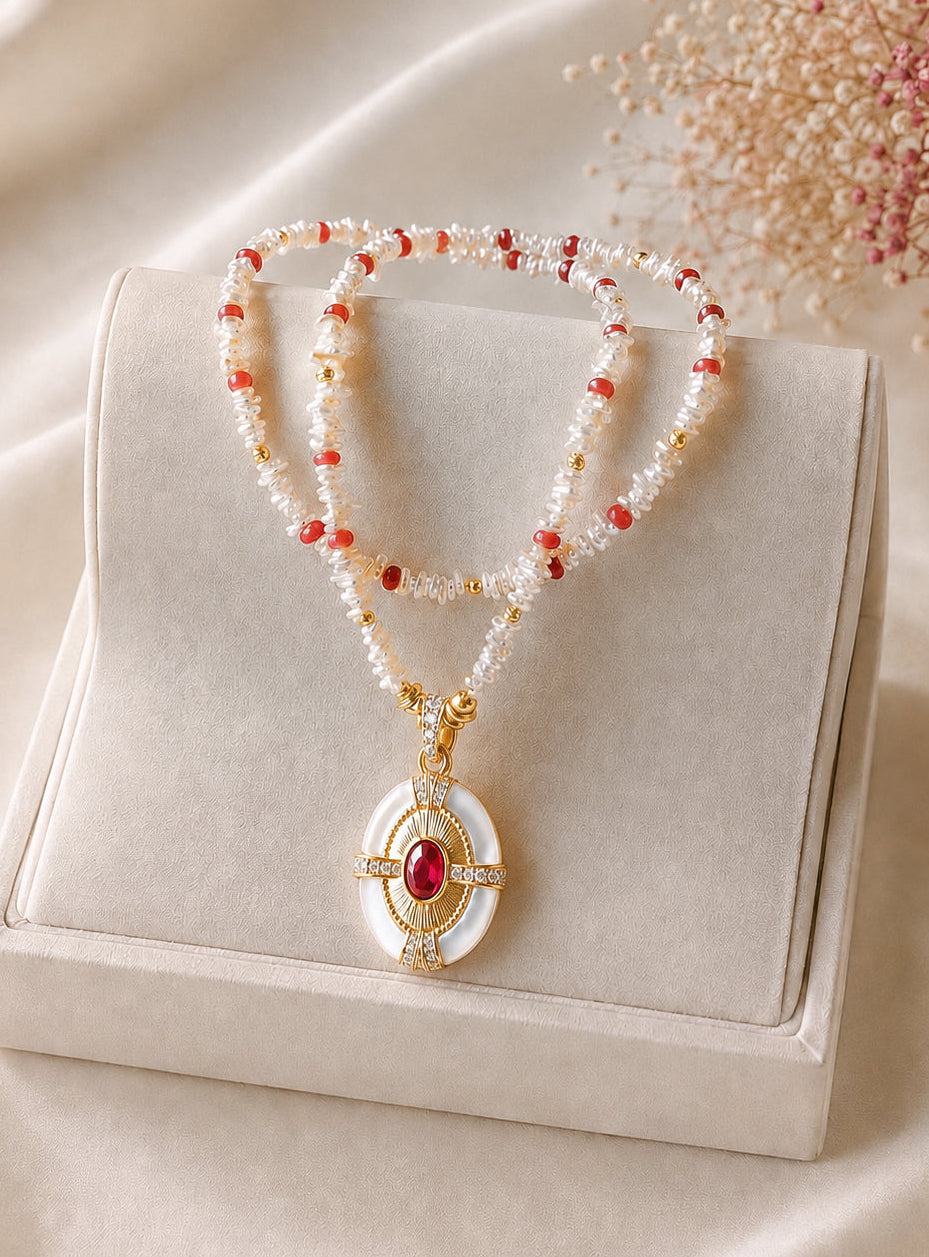 Keshi pearl necklace with red ruby bead accents and gold circular pendant in a box