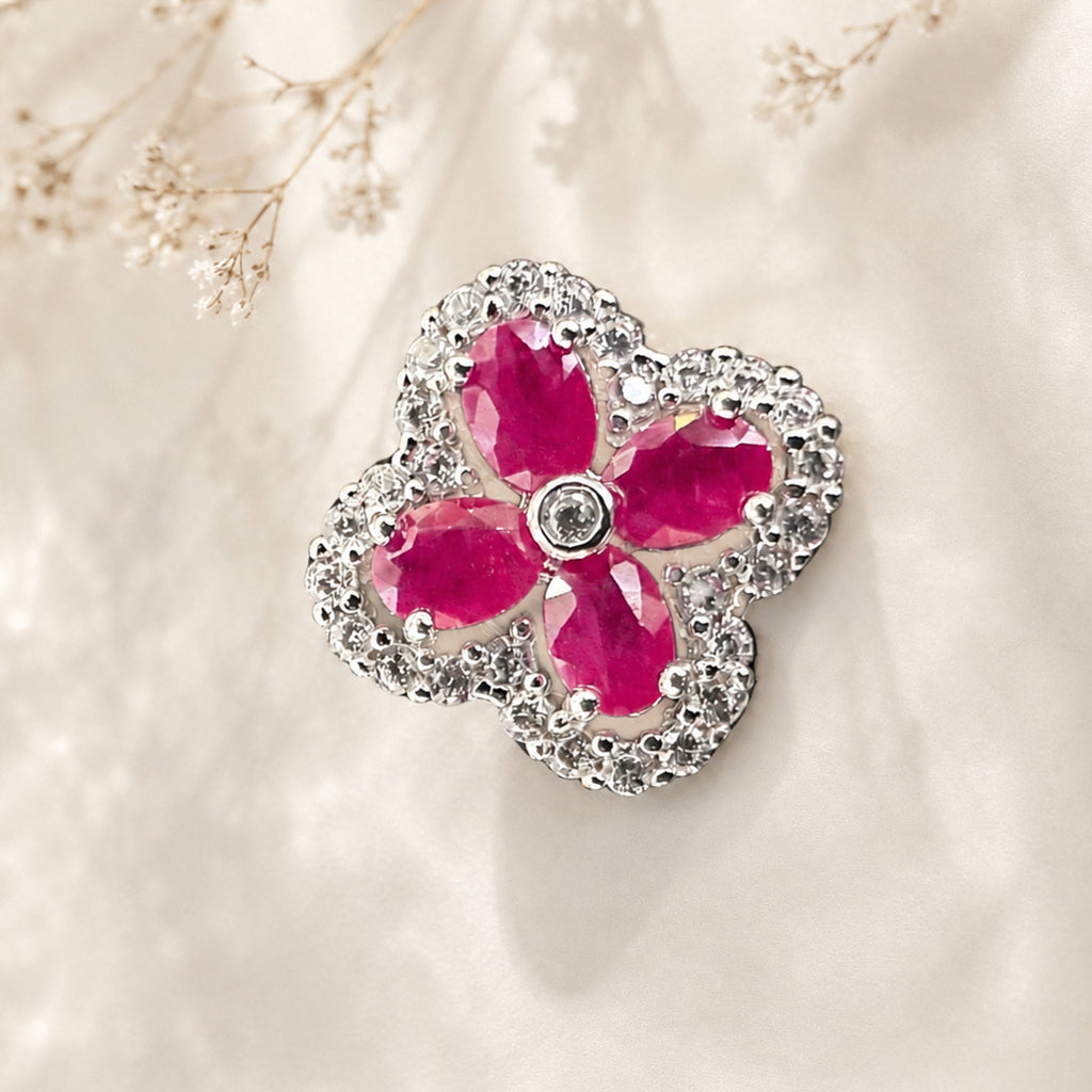 Close-up of sterling silver clover pendant with four pink-red gemstones and a halo
