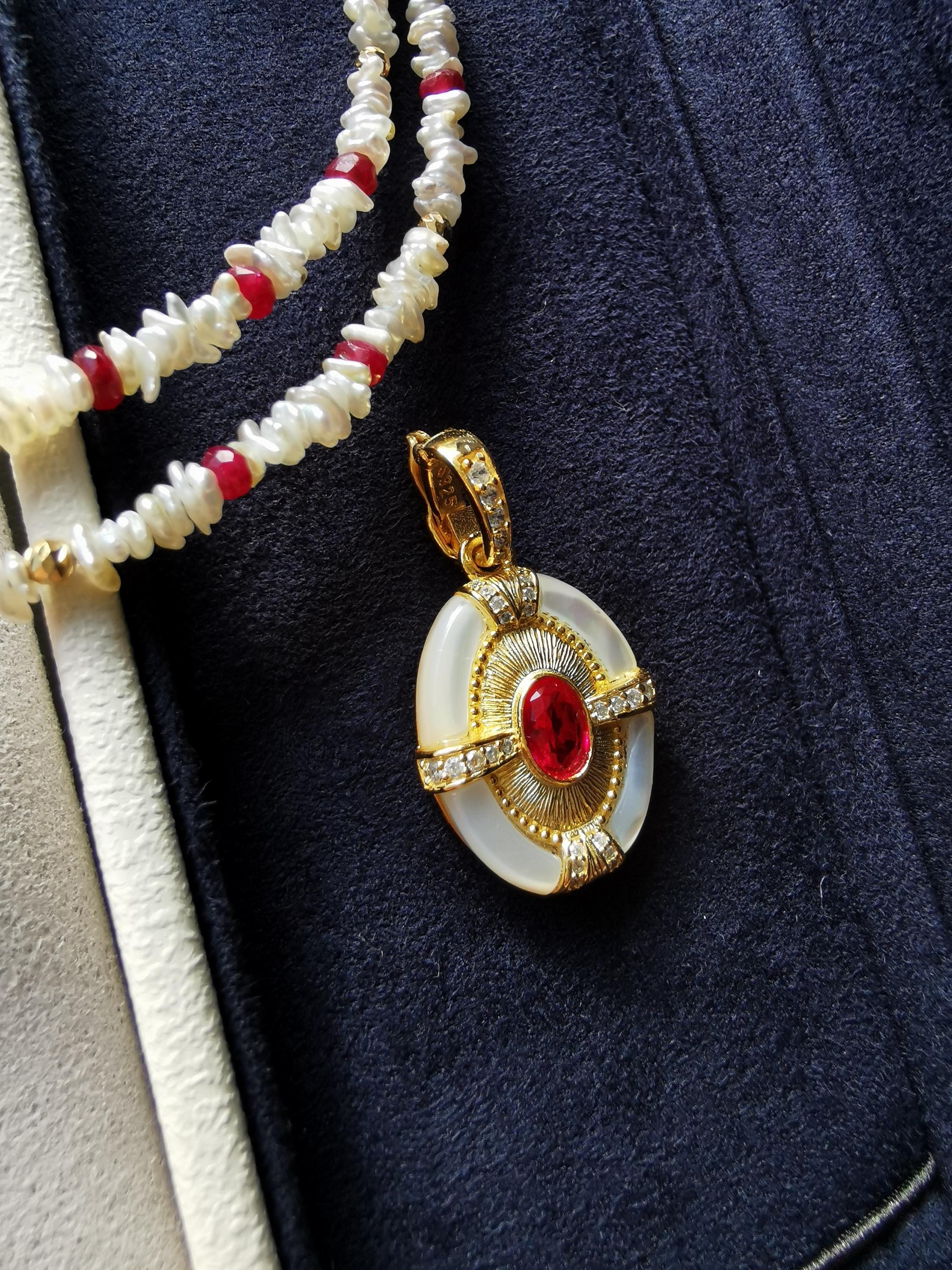 Gold oval pendant with red stone and mother-of-pearl, with white and red bead strands
