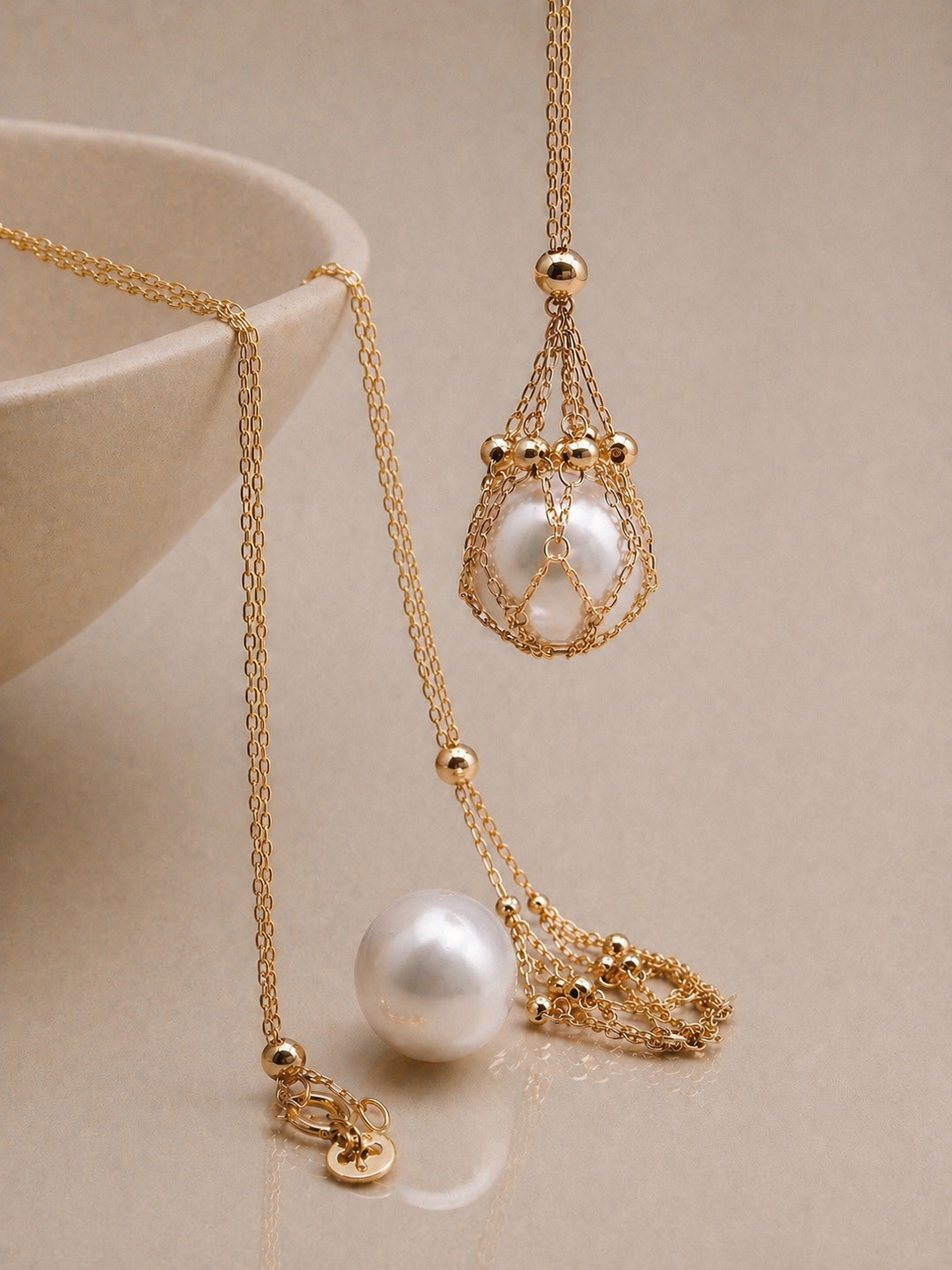 Gold tone layered pendant necklace with teardrop net charm and pearl bead details