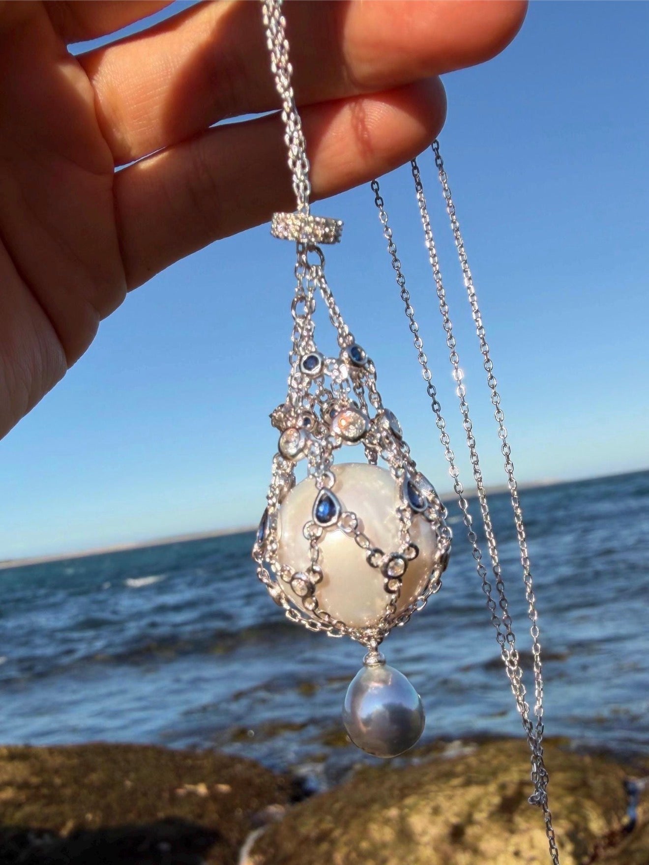 Openwork teardrop pendant necklace with blue stones and pearl drop on chain