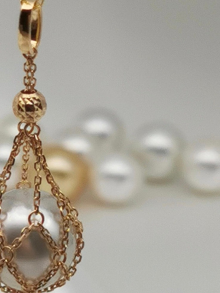 Gold net pendant with teardrop pearl, close-up on chain links