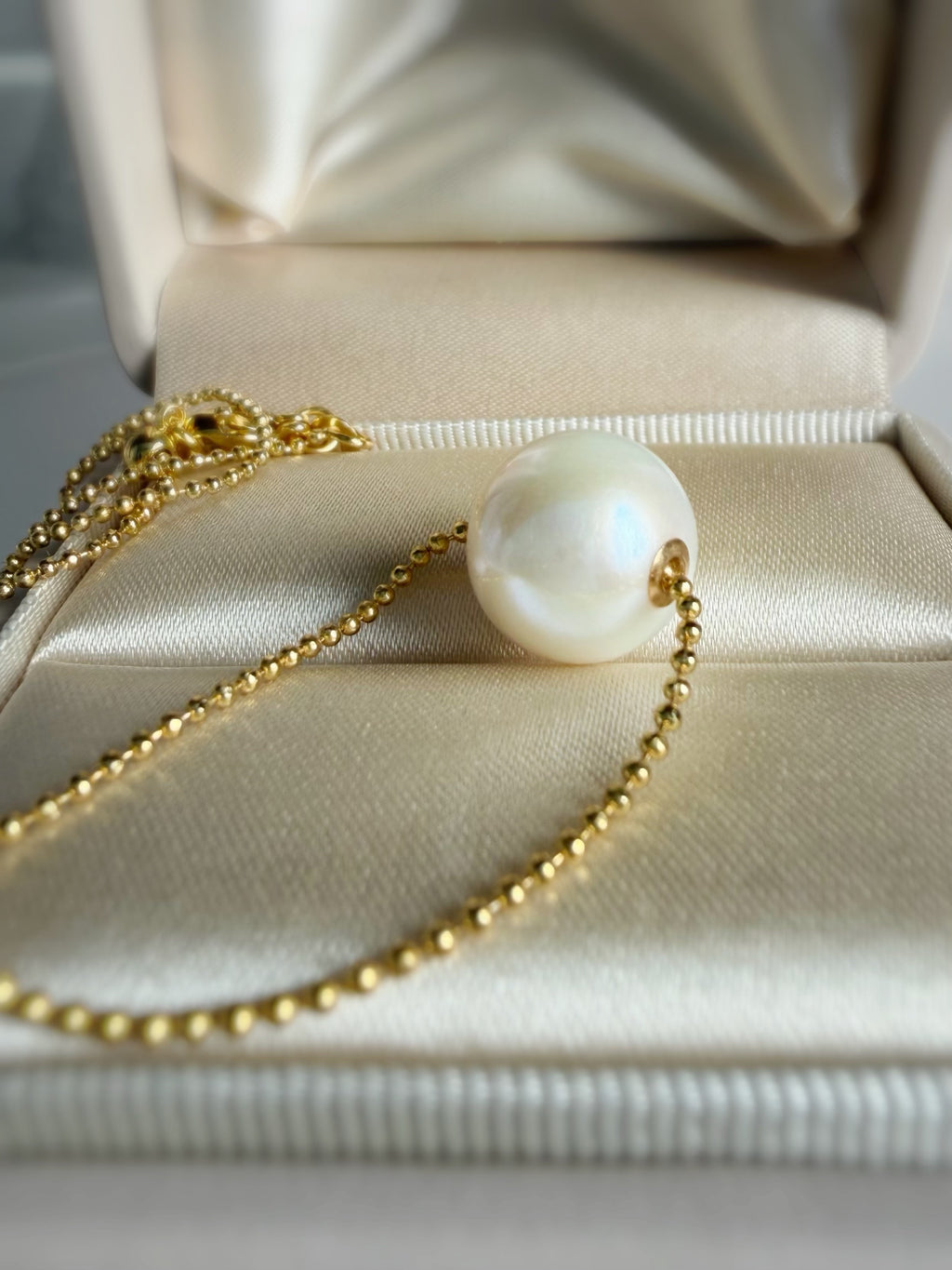 Freshwater pearl pendant necklace with gold-tone chain on jewelry box