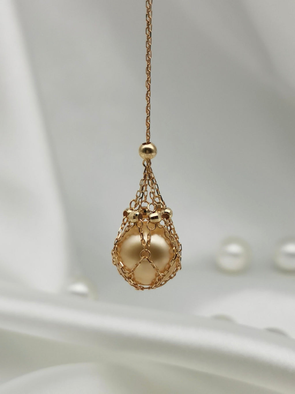 Gold tone teardrop net pendant necklace with golden pearl bead detail