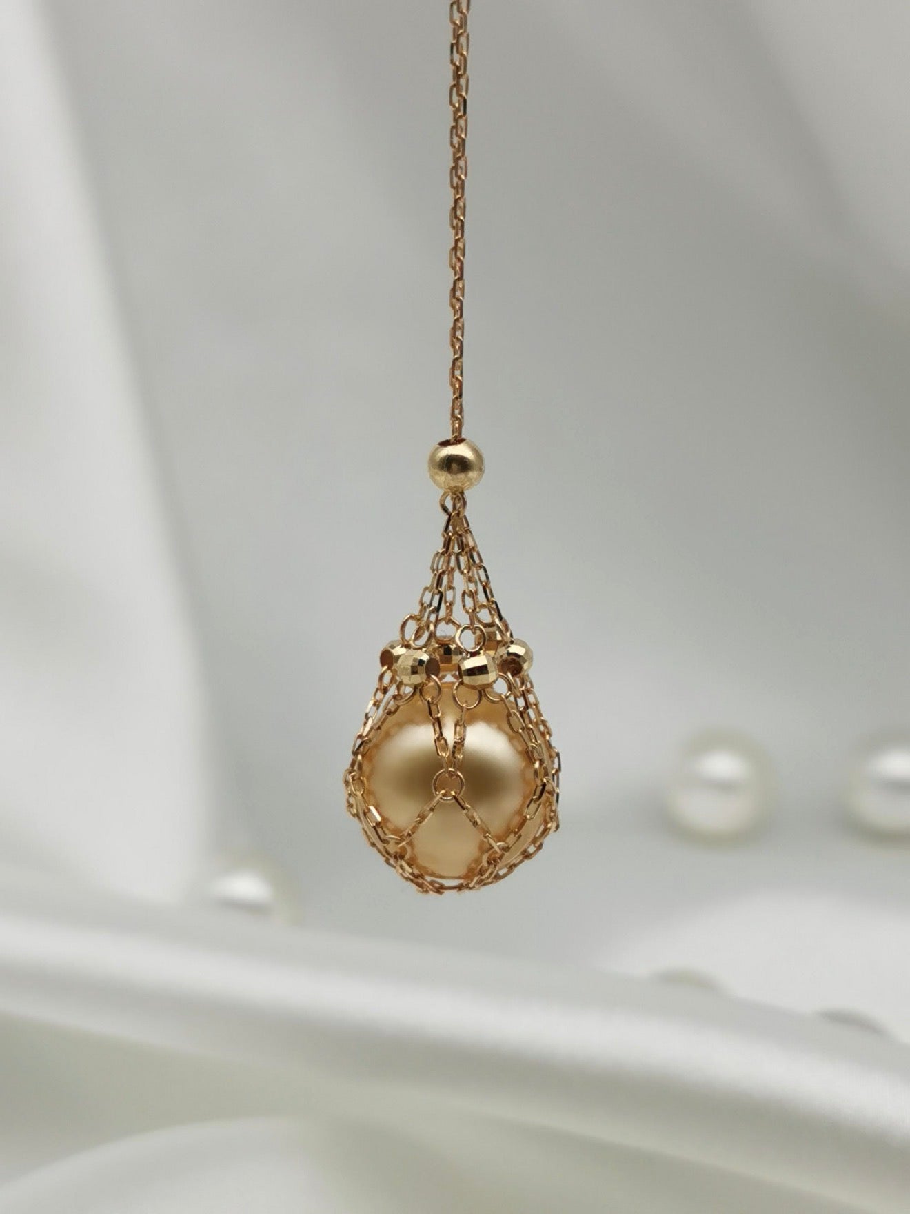 Gold tone teardrop net pendant necklace with golden pearl bead detail