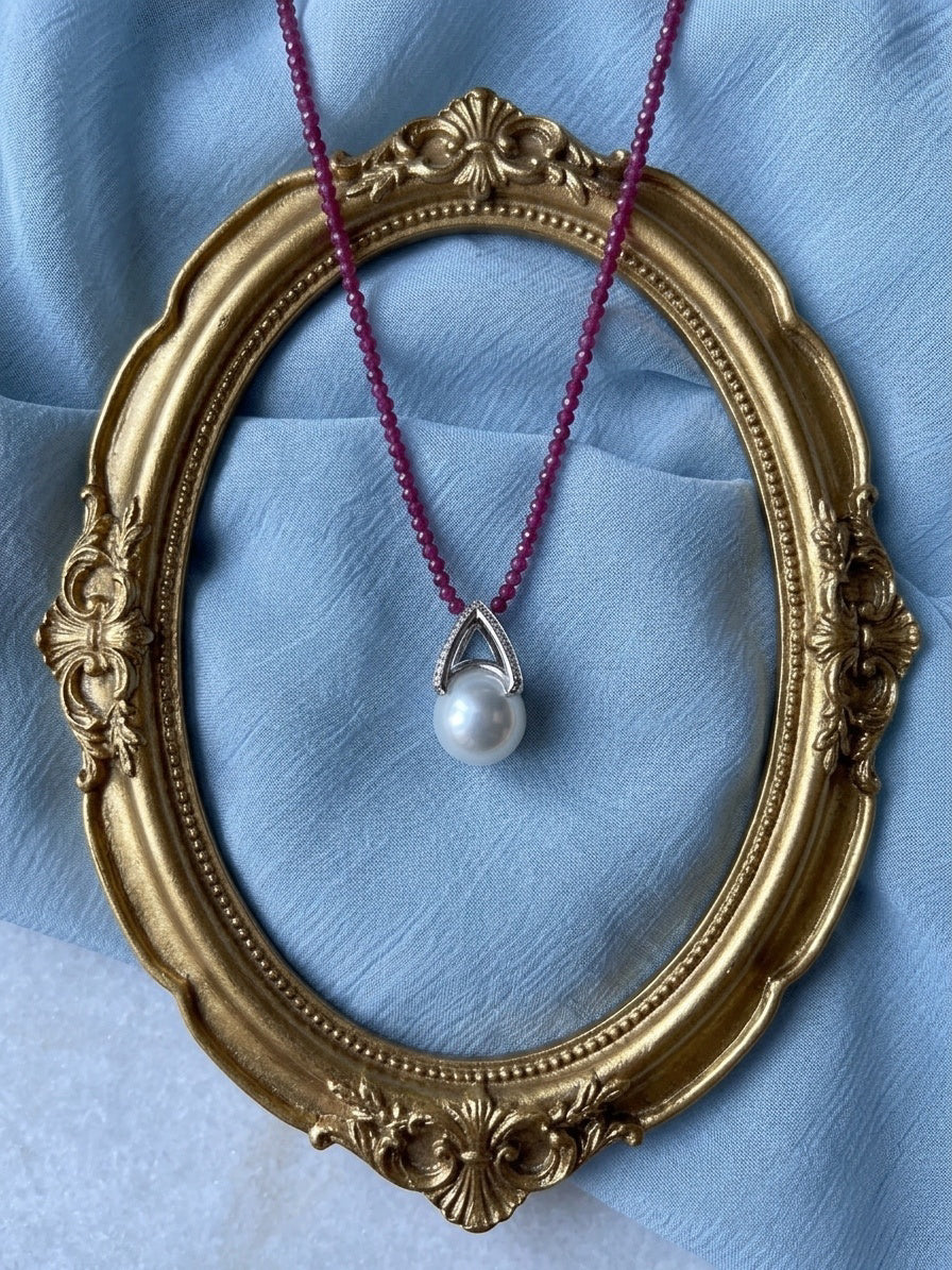 Pear-shaped freshwater pearl pendant on red beaded cord with teardrop metal surround