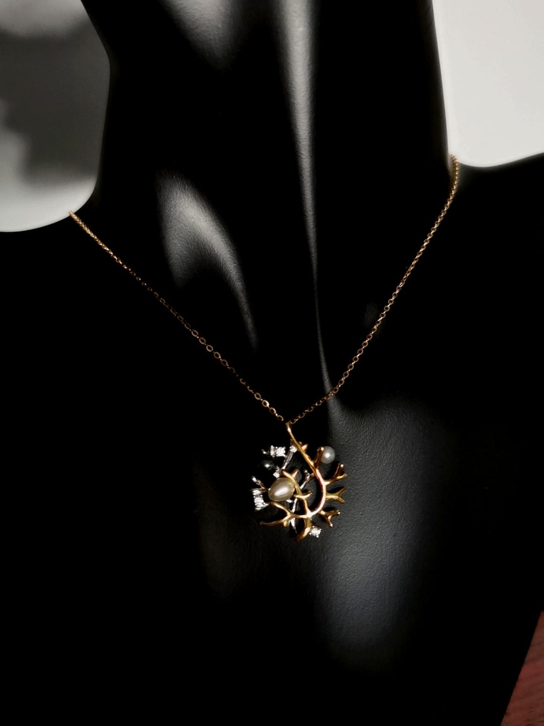 Silver necklace with beaded chain and small branch pendant featuring pearls and crystals.