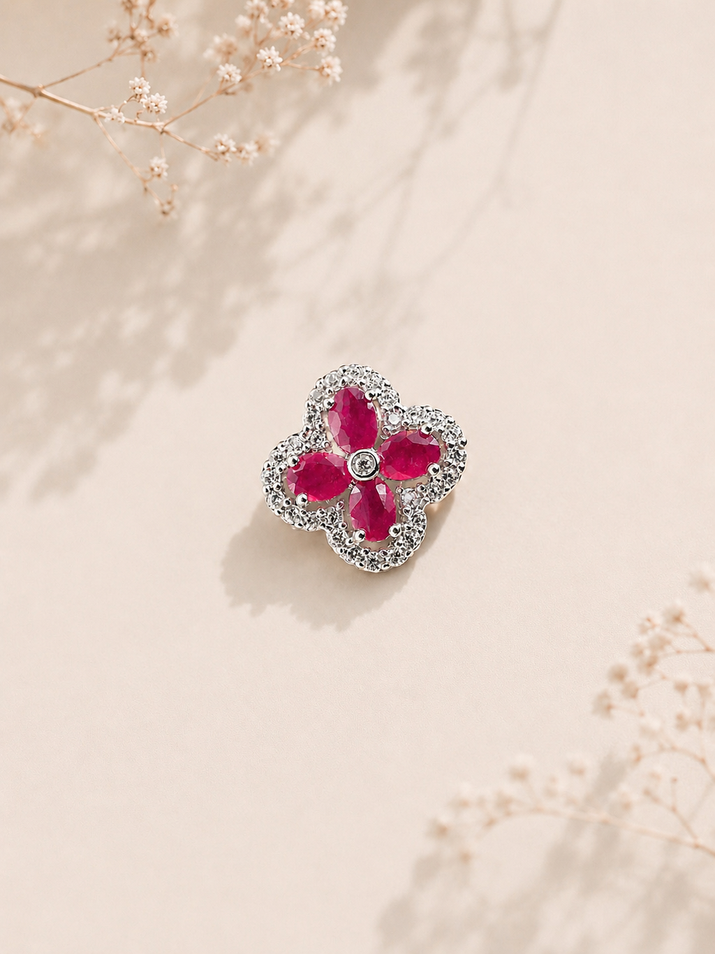 Four-leaf clover pendant with pink-red gemstones in a silver halo setting