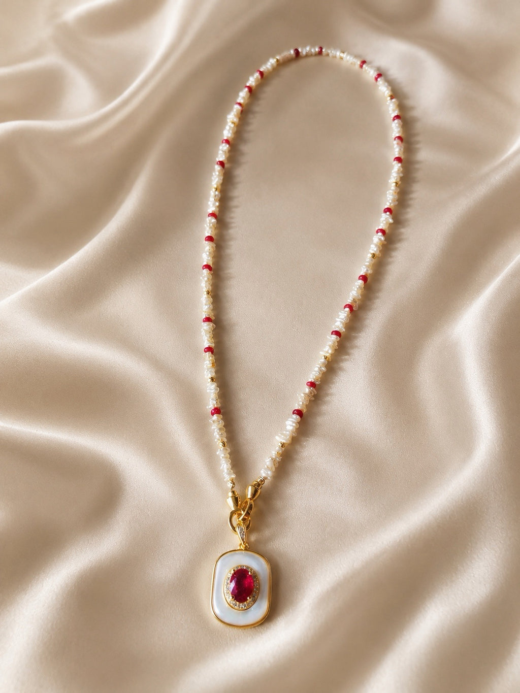 Beaded necklace with red and white beads and a gold-tone mother-of-pearl ruby pendant