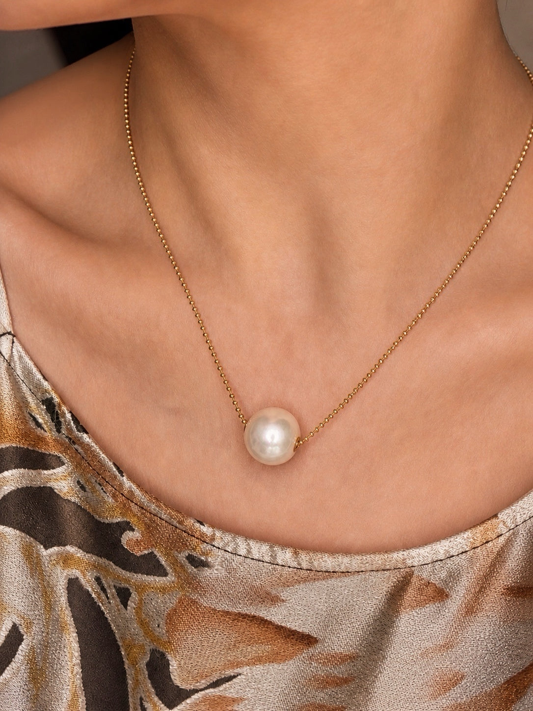 Gold-tone chain necklace with small white freshwater pearl pendant on collar