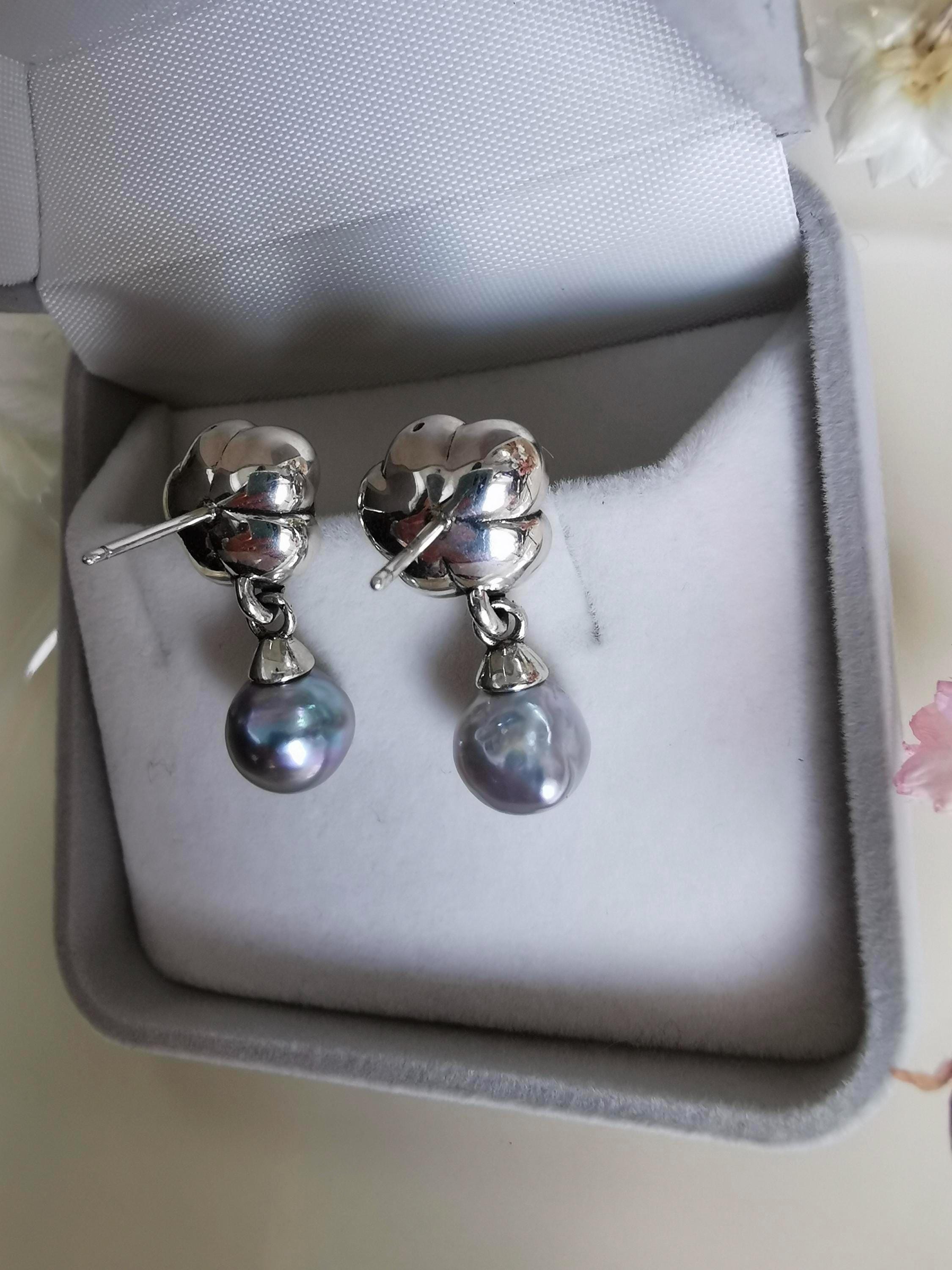 Pair of silver rose earrings with pearl drop charms displayed in a box