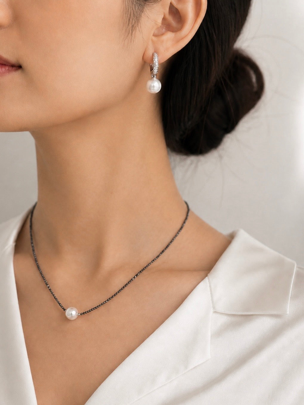 Silver hoop lock earrings with pavé hoops and round pearl drops on model’s ear
