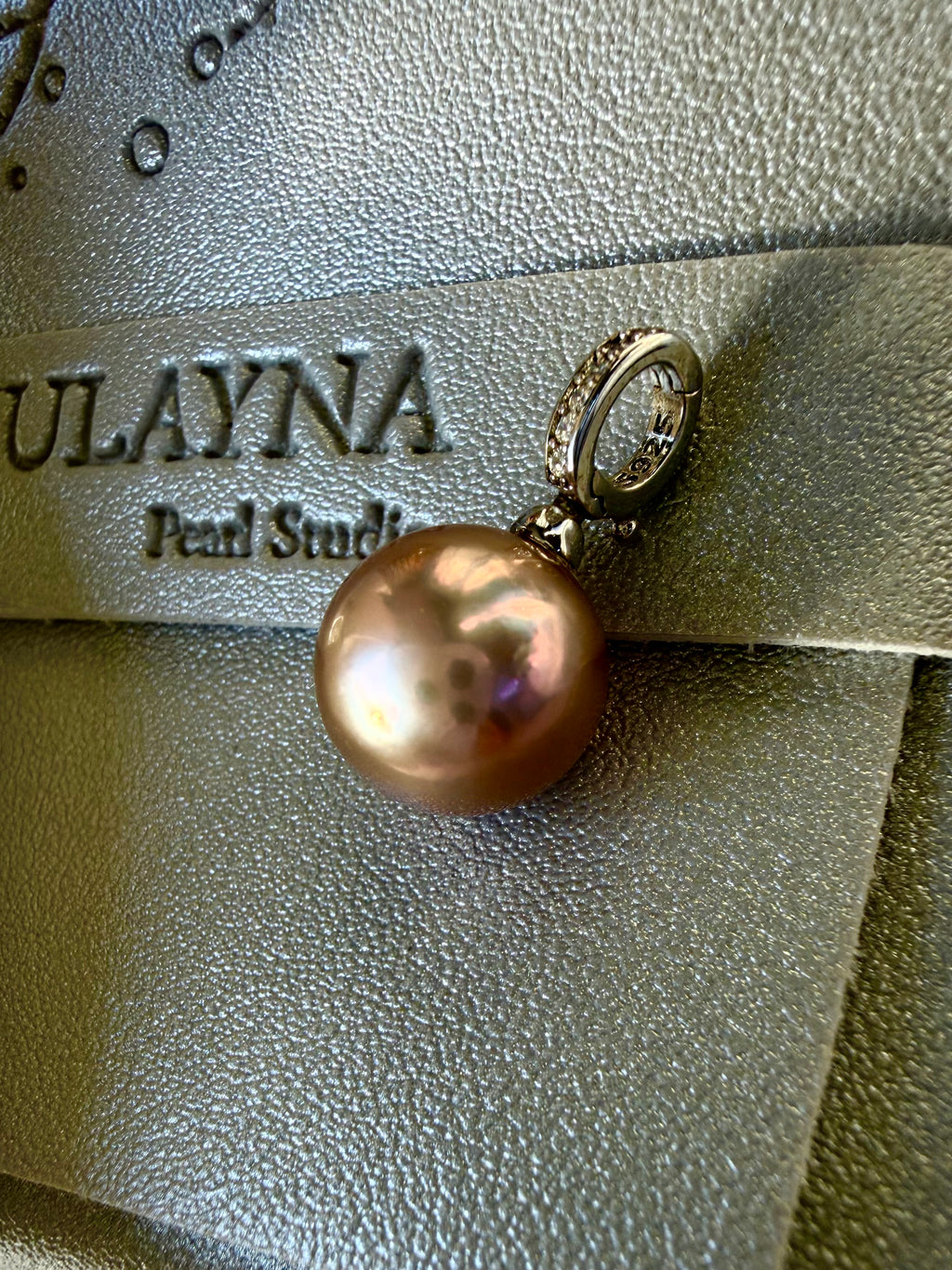 Round pearl pendant with gold-toned loop and rhinestone top, close view