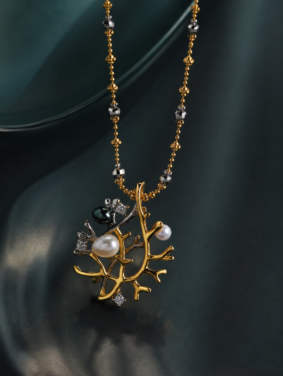 Silver necklace with beaded chain and branch pendant featuring pearls and crystals.