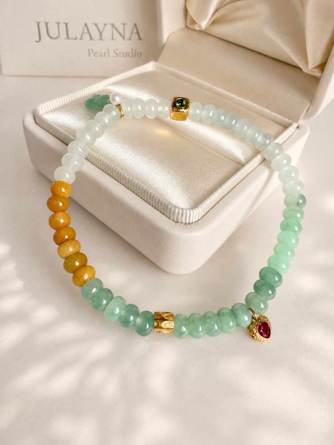 Jadeite beaded bracelet with white and mint beads, gold cube charm, and red gemstone drop