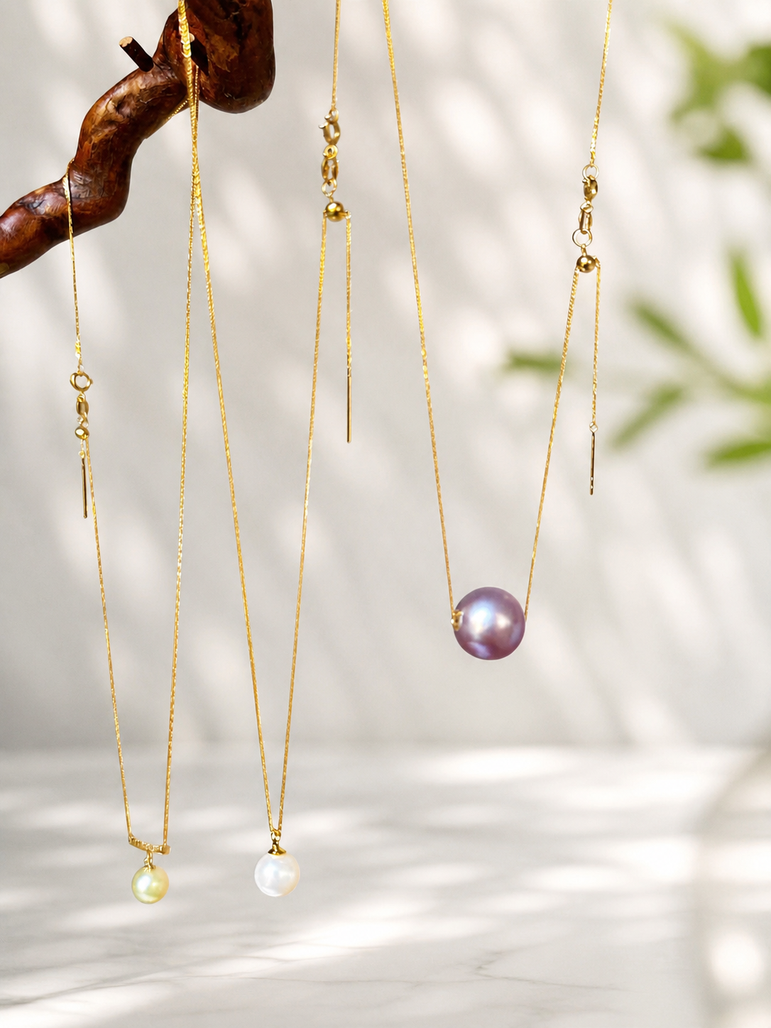 Gold pearl pendant necklaces with purple pearls hanging on chains
