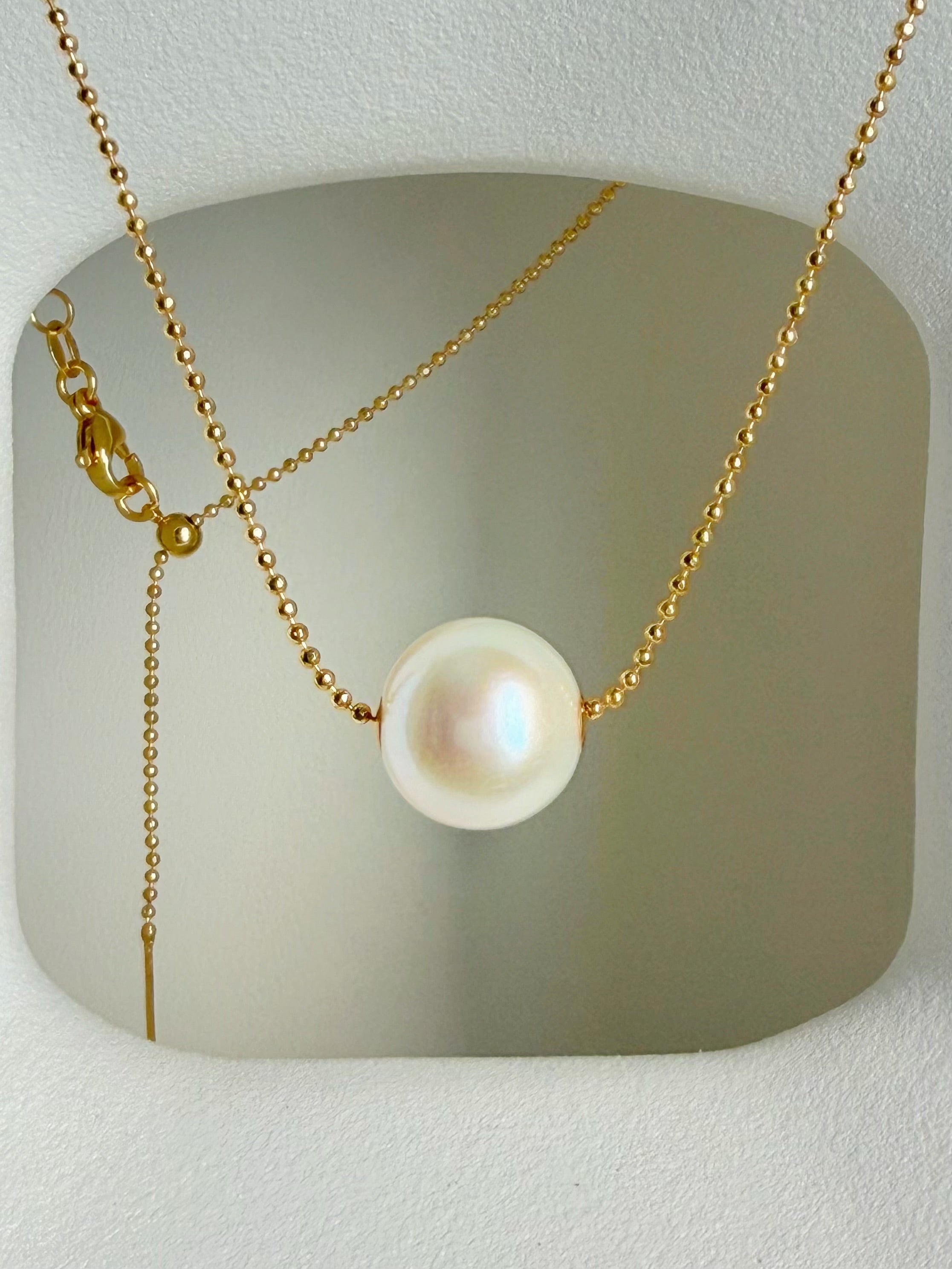 Gold-tone chain necklace with single white freshwater pearl pendant, front view