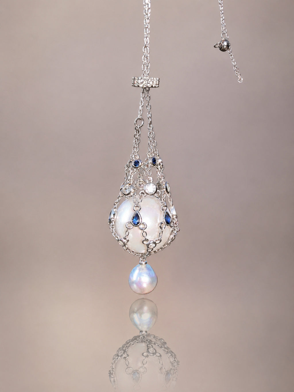 Pendant necklace with silver-toned openwork teardrop design, blue accents, and round drop pearl