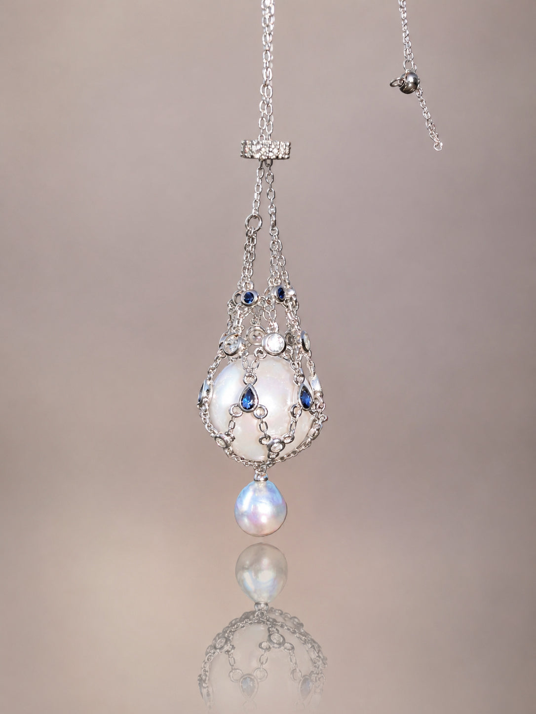 Pendant necklace with silver-toned openwork teardrop design, blue accents, and round drop pearl