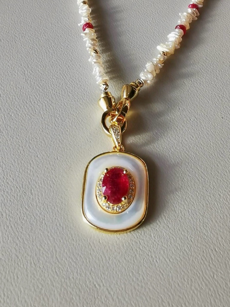Gold-framed ruby and mother-of-pearl pendant on red-and-ivory bead necklace