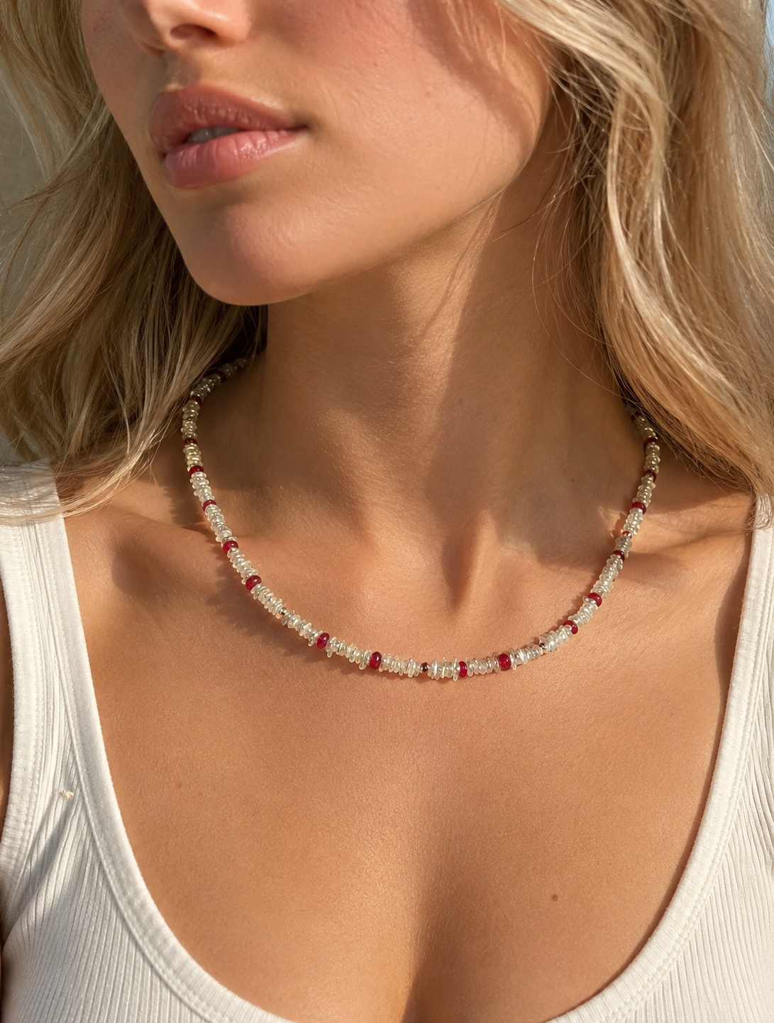 Keshi pearl necklace with ruby pendant and red bead accents on model