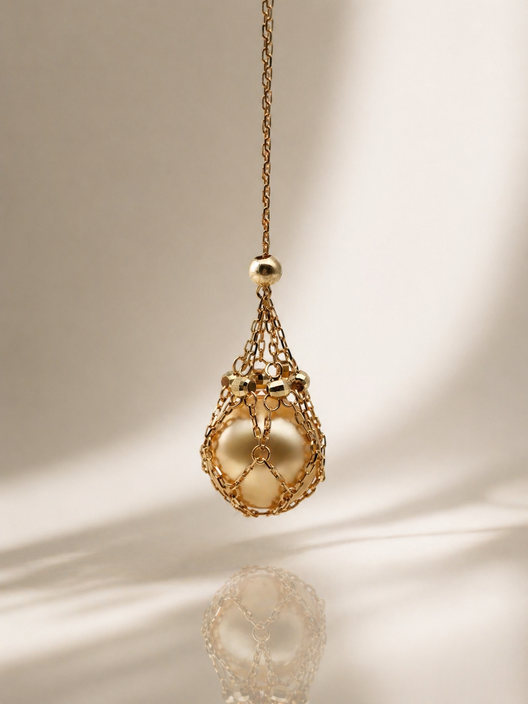 Gold tone teardrop net pendant necklace with dangling pearl bead charm