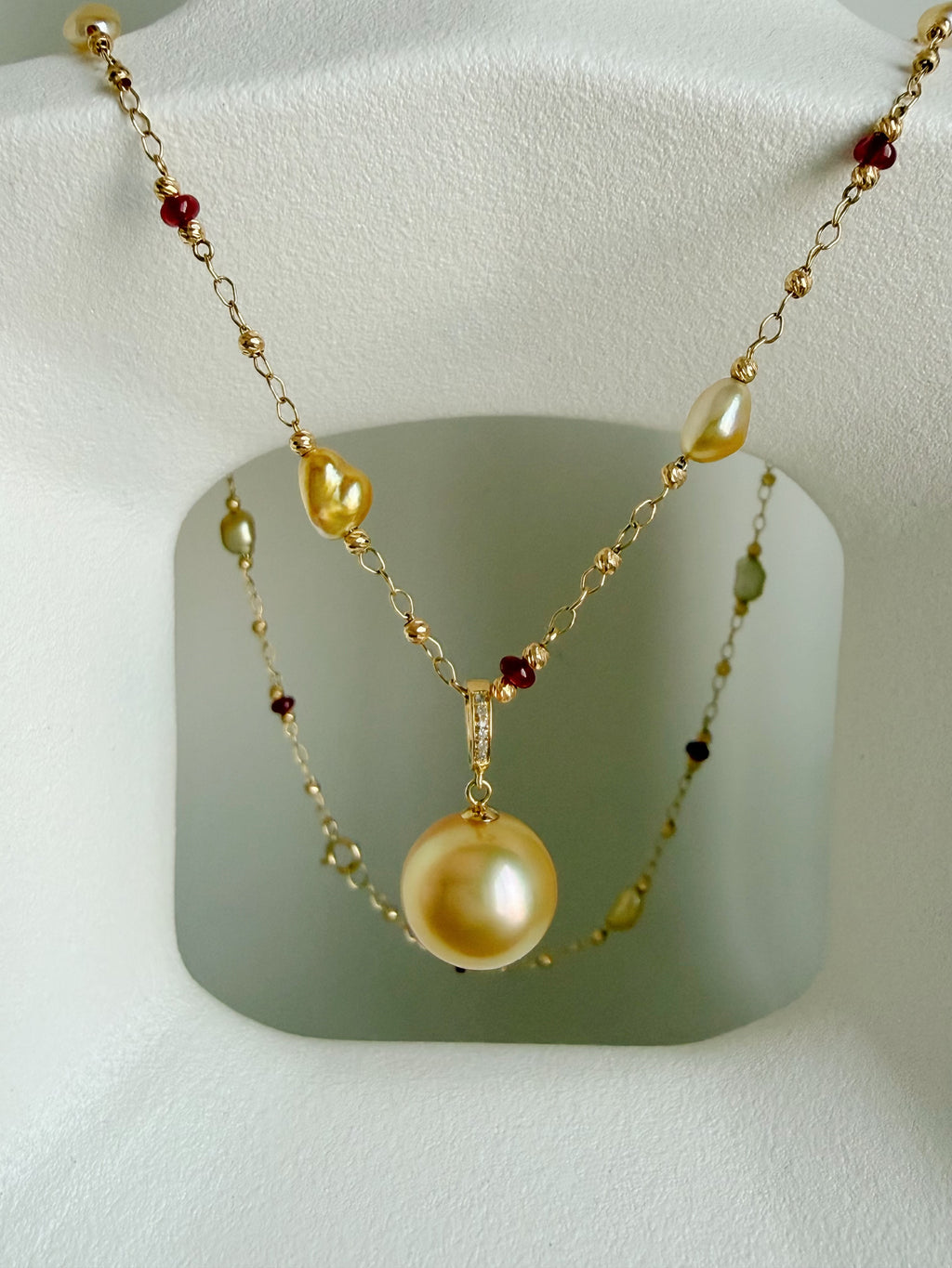 Gold pearl pendant necklace with red gemstone beads and layered chain design