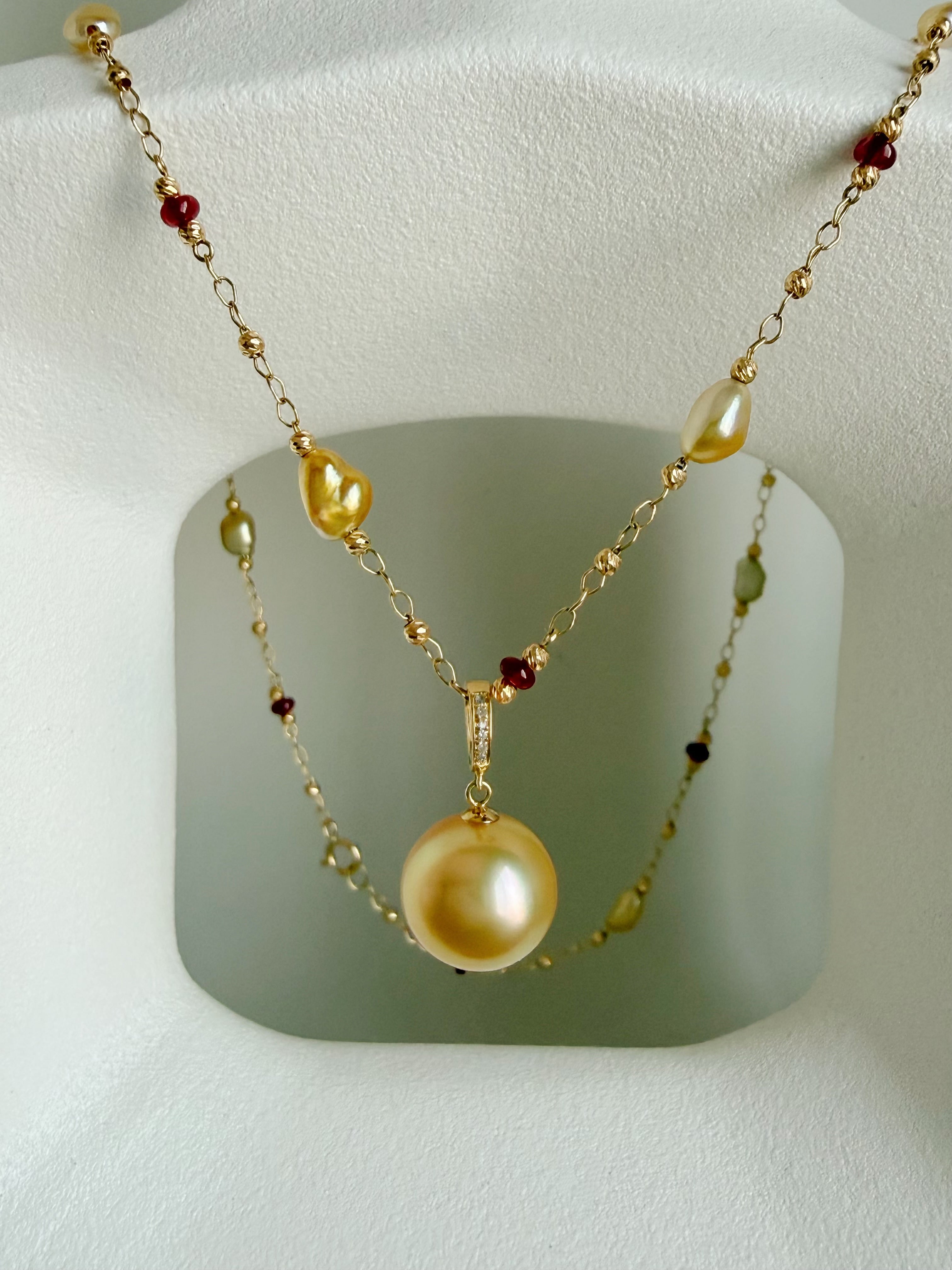 Gold pearl pendant necklace with red gemstone beads and layered chain design