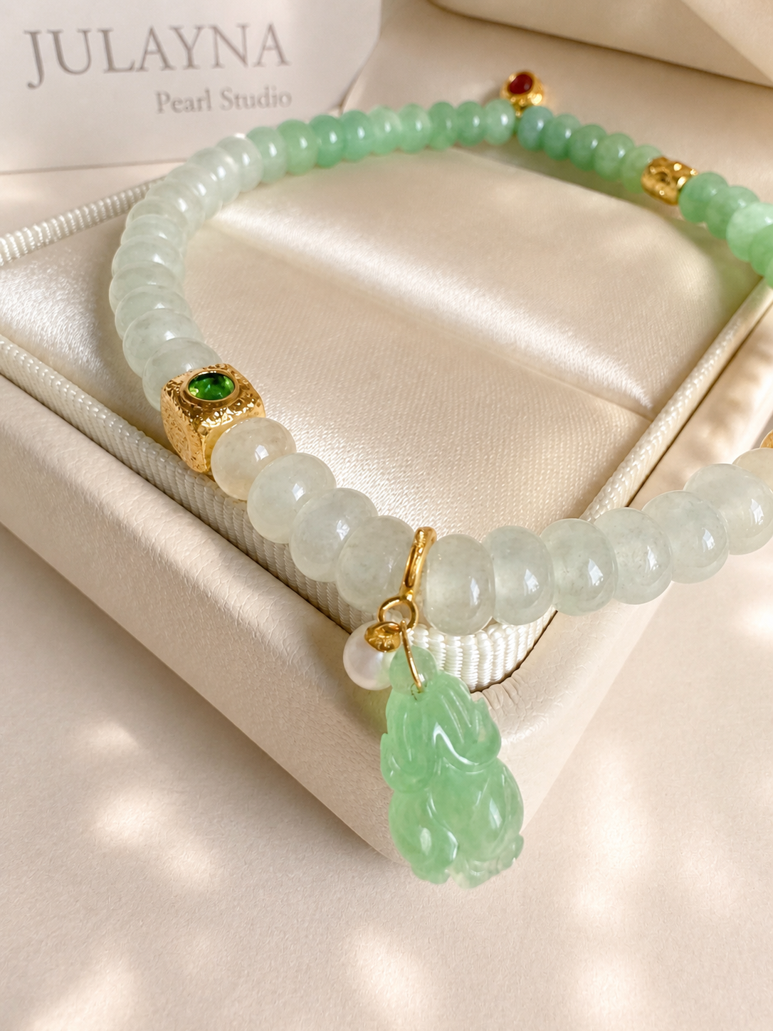 Jadeite beaded bracelet with light green and white beads, gold charms, and green carved pendant