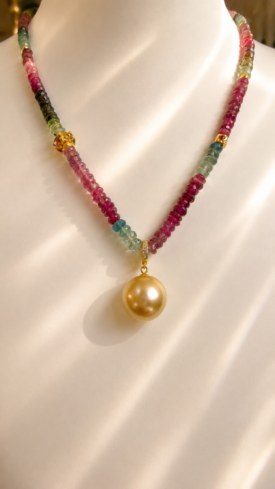 Gold pearl pendant necklace with pink, green, and gold bead details at the center
