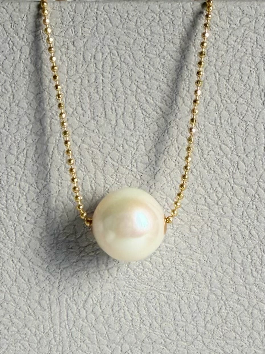 Gold-tone chain necklace featuring a round white freshwater pearl pendant