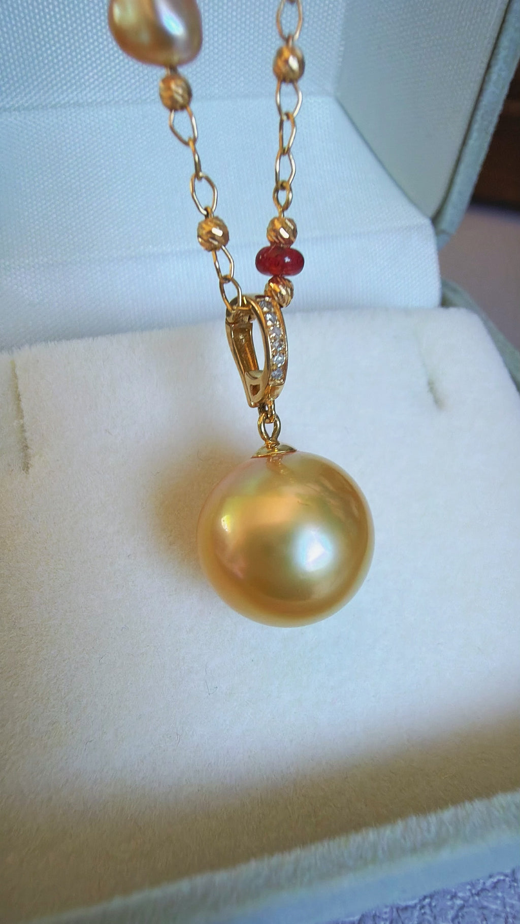 Gold pearl pendant necklace with layered gold chains and small red and clear beads