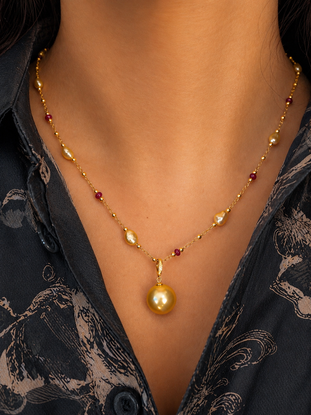 Gold pearl pendant necklace on model, featuring short layered strands with red and gold beads