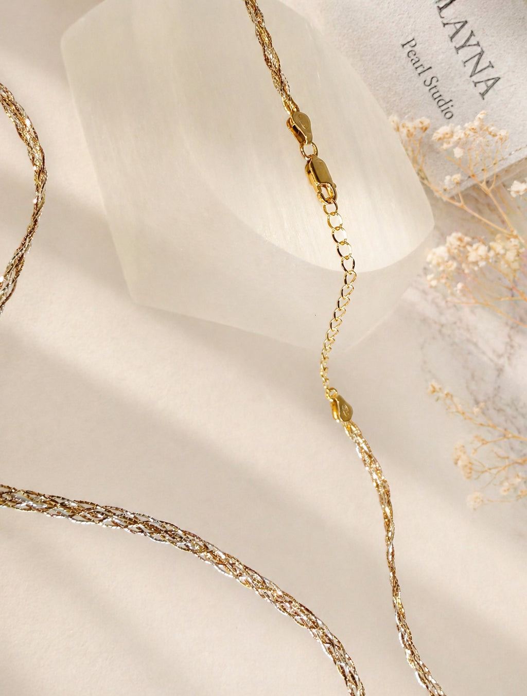 Three-tone gold braided necklace detail with small gold links and clasp