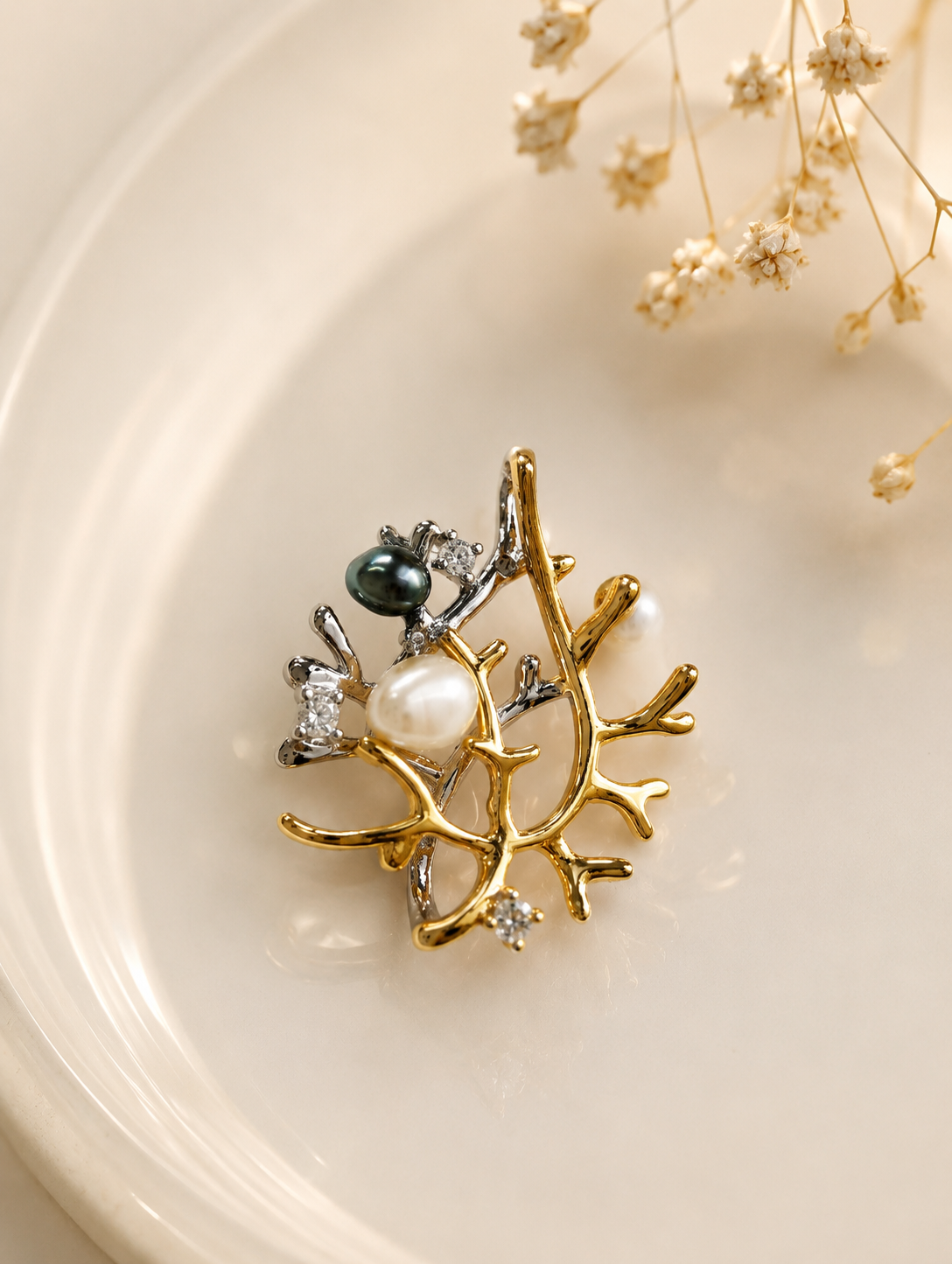 Branch-style pendant charm with pearl, dark bead, and rhinestone accents on gold-tone settings