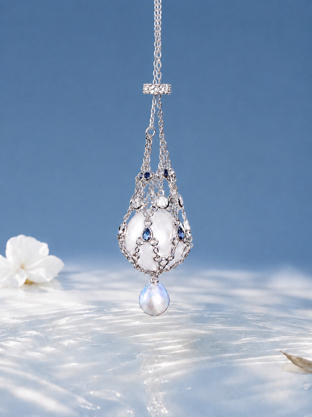 Pendant necklace with openwork silver-toned frame, blue accents, and a large teardrop pearl