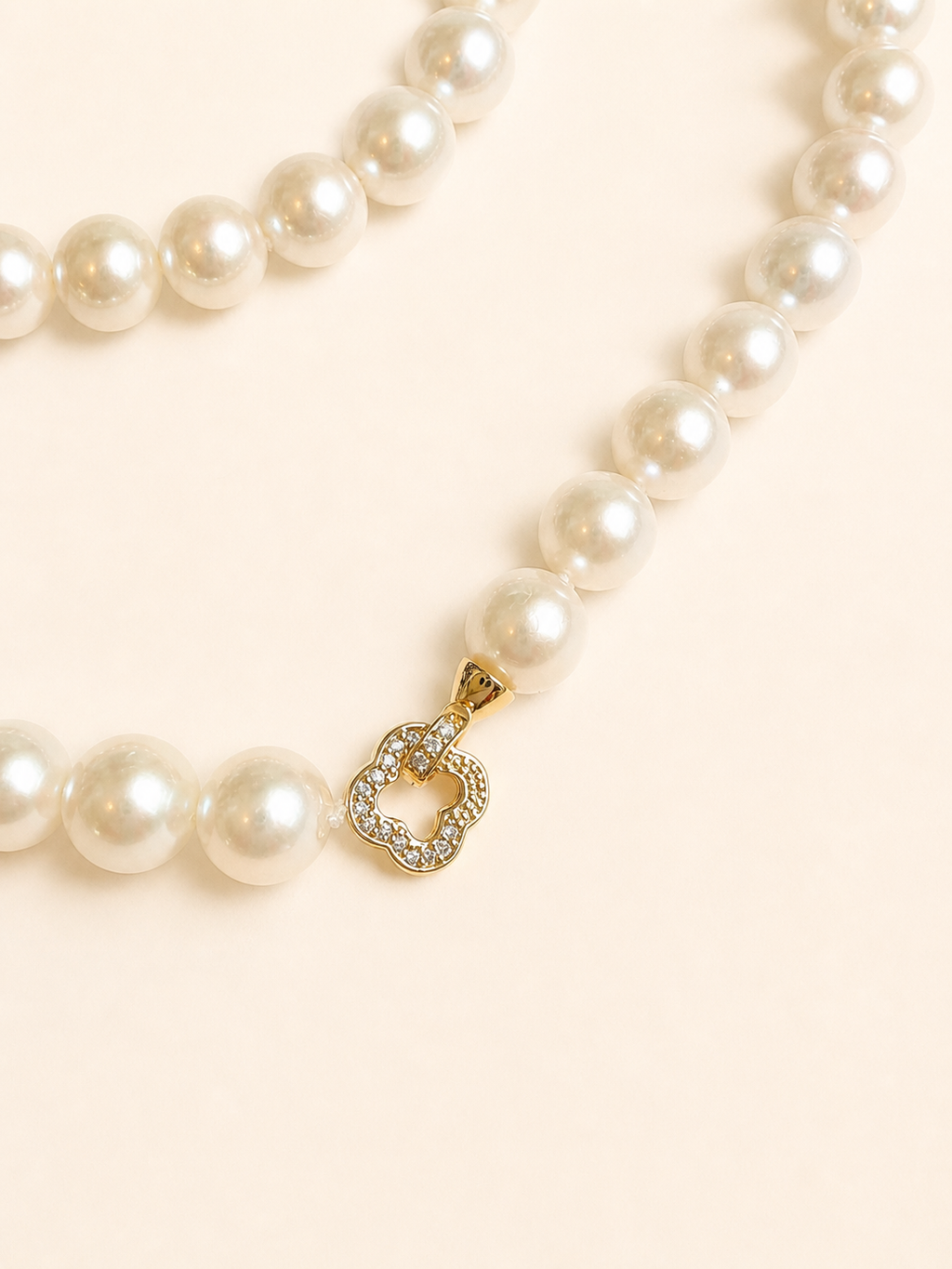 Single strand pearl necklace with gold-tone clover charm and small crystal accents