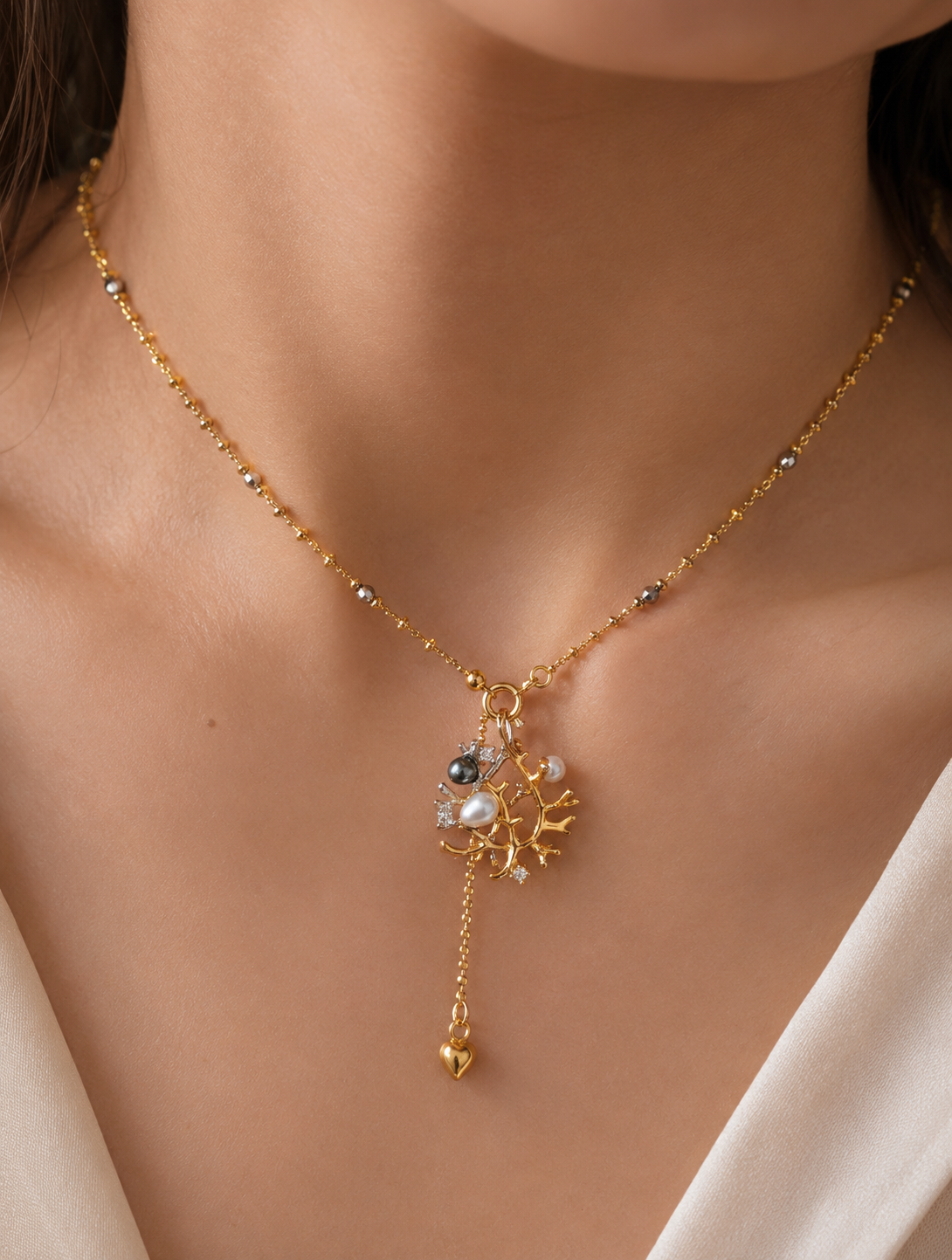 Silver necklace with short beaded chain and branch pendant featuring pearls and crystal details.